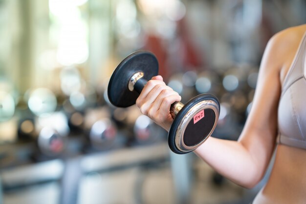 Zamyka w górę kobiet z dumbbells w rękach gym Premium Zdjęcia