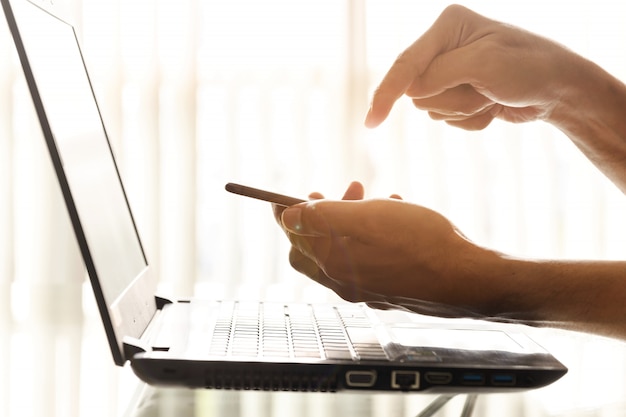 Zbliżenie ręce przedsiębiorców używają smartfonów i laptopów w biurze. Premium Zdjęcia
