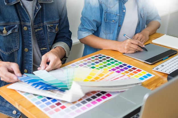 Zespół grafików pracujących nad projektowanie stron internetowych za pomocą próbek kolorów edycji grafiki za pomocą tabletu i rysika w biurach w zajęty creative office. Premium Zdjęcia