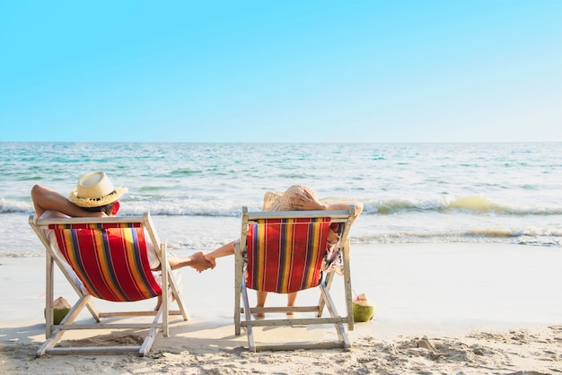 Zrelaksuj się para położyć się na plaży chiar z falą morską - mężczyzna i kobieta mają wakacje na morzu natury koncepcji Darmowe Zdjęcia