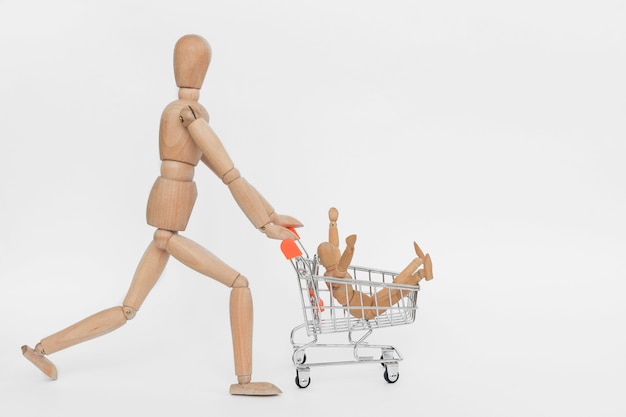 Adicta a las compras. hombre de madera montando carrito de compras con otro sentado en él. aislado en blanco Foto Premium