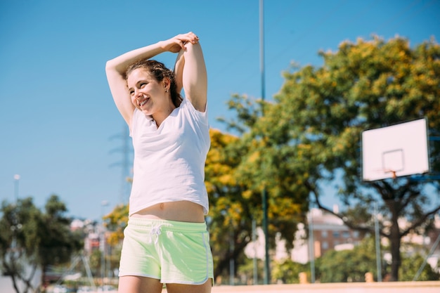 Adolescente femenino encantado juguetón que calienta al aire libre Foto gratis