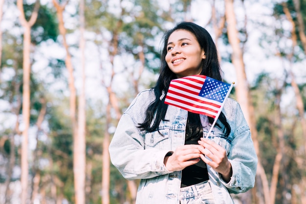 Adolescente hispana, tenencia, bandera estadounidense, en, palo Foto gratis