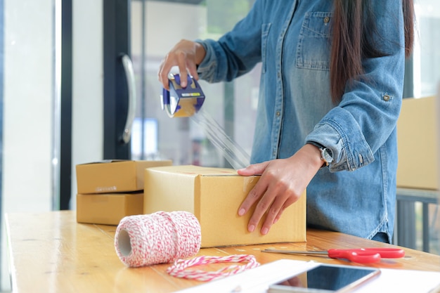 Las adolescentes empacan productos en cajas y usan cinta adhesiva transparente para entregar a los clientes. Foto Premium 