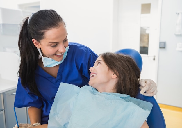 Alegre dentista pediátrico con un sonriente paciente joven Foto Premium