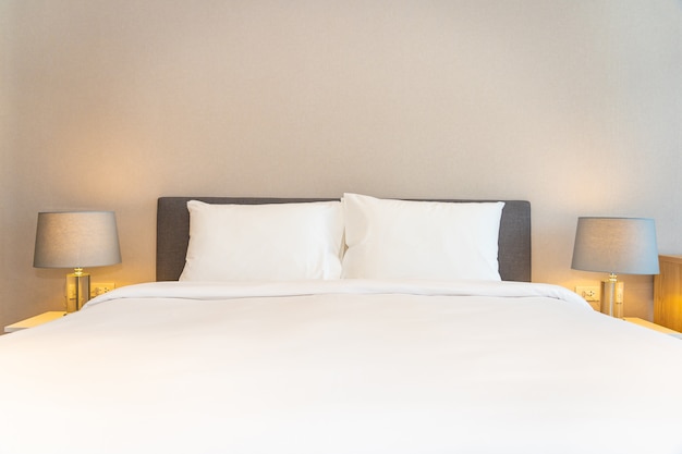 Almohadas blancas en la cama con lámparas de luz Foto gratis