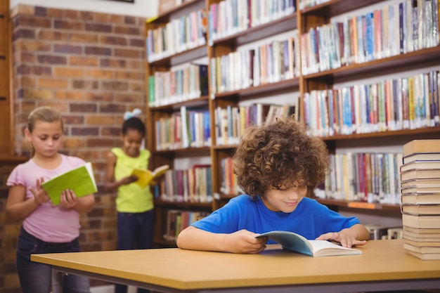 Alumno feliz leyendo un libro de la biblioteca en la escuela primaria ...