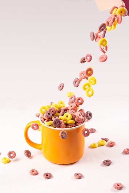 Anillos De Cereales De Colores Cayendo En Una Taza Naranja Sobre Fondo