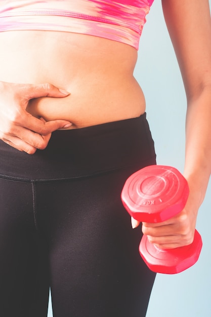 Aptitud femenina en pantalones negros y sujetador deportivo rosa sosteniendo pesas rojas Foto Gratis