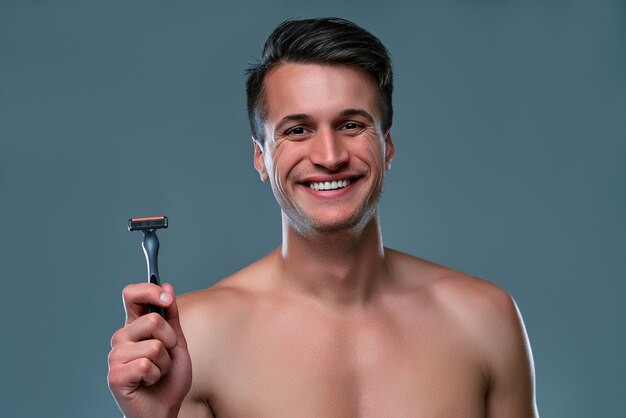 Apuesto joven aislado retrato de hombre musculoso sin camisa está de pie sobre fondo gris con