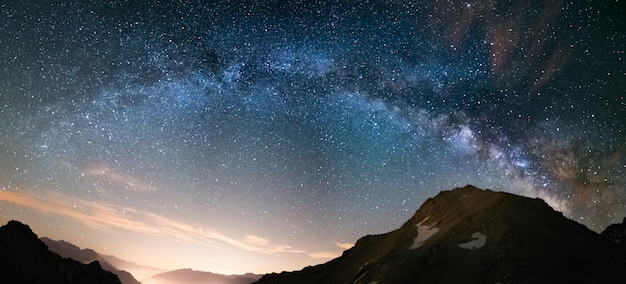 Arco de la vía láctea y cielo estrellado en los alpes. vista panorámica, fotografía astronómica, observación de estrellas. contaminación lumínica en el valle de abajo. Foto Premium