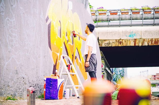 Artista Callejero Pintando Un Colorido Graffiti En Una Pared Gris