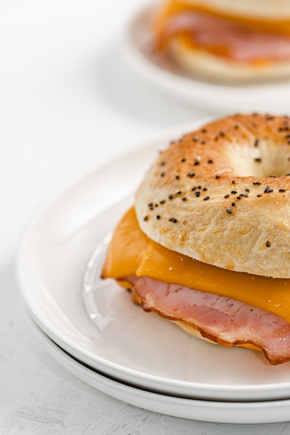 Bagel con jamón y queso cheddar en la placa blanca Foto Premium