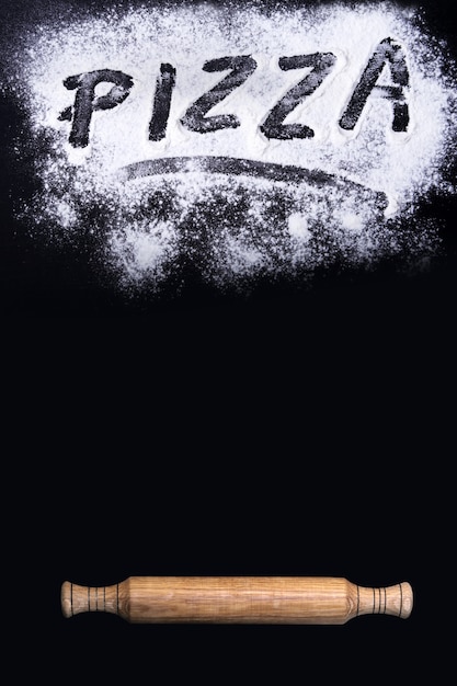 Banner con la inscripción pizza, rodillo y harina sobre una mesa negra. fondo con espacio libre para su texto. Foto Premium