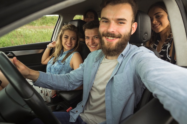 Barba joven sentado con su amigo en el coche tomando selfie Foto gratis