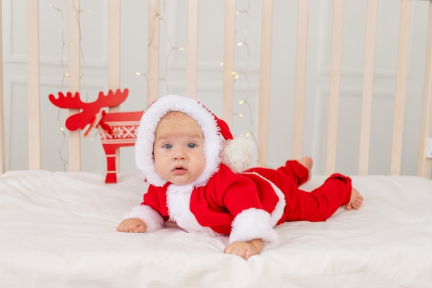 Bebe De 6 Meses En Un Traje De Papa Noel Acostado En Una Cuna En Casa Boca Abajo Foto Premium