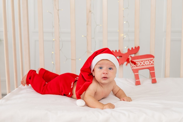 Bebe De 6 Meses En Un Traje De Papa Noel Acostado En Una Cuna En Casa Boca Abajo Foto Premium