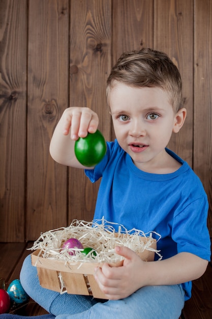 Bebe Feliz Con Una Canasta De Huevos De Pascua En La Pared De Madera Foto Premium