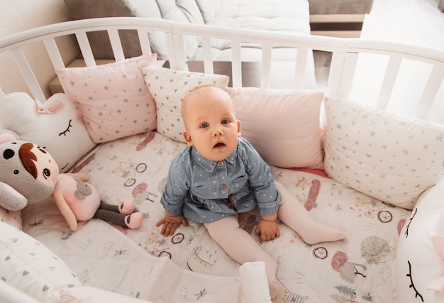 Un Bebe De Nina Bonita Se Sienta En Una Cuna Una Mirada A La Camara Bebe En Una Cuna Foto Premium