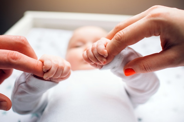 Bebe Recien Nacido En La Guarderia Mama Y Papa Sostienen Al Bebe De Las Manos De Cerca Foto Premium