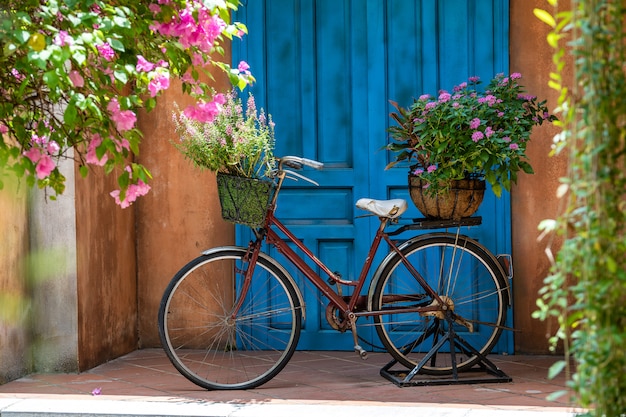 Bicicleta vintage con cesta llena de flores junto a un antiguo edificio en danang, vietnam, cerca | Foto Premium