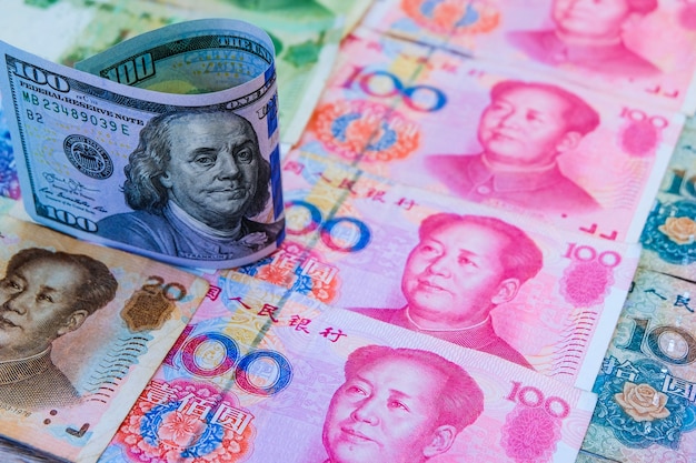 Billete de dólar americano que se coloca sobre los billetes de banco de yuan chinos. Foto Premium 