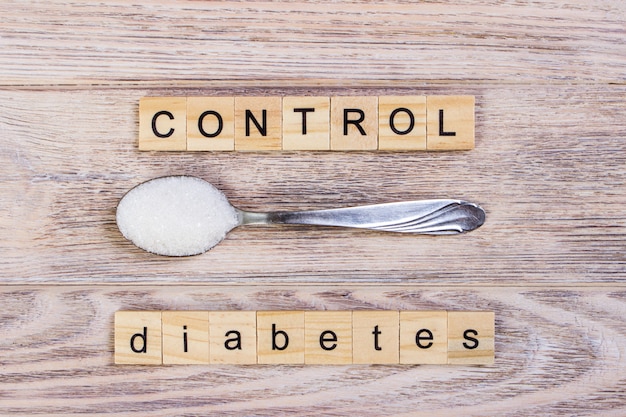 Bloques de control de diabetes letras de madera y pila de azúcar en una cuchara Foto Premium 