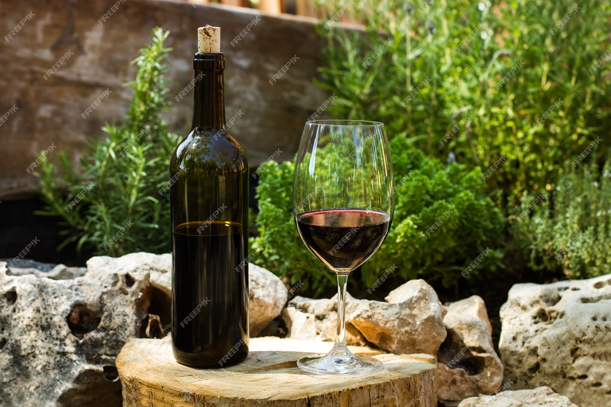 Una Botella Y Una Copa De Vino Tinto En El Jardín Con Piedras Y Hierbas