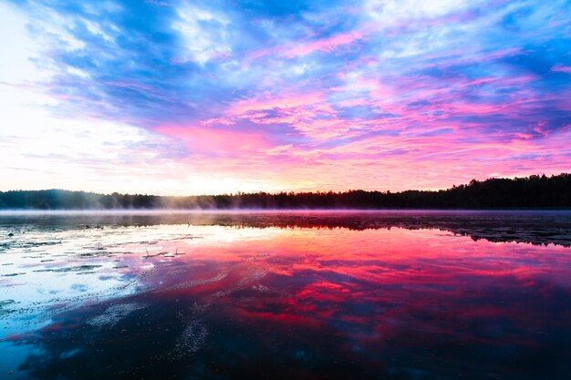 Brillante colorido atardecer brumoso en el lago con nubes y reflejos ...
