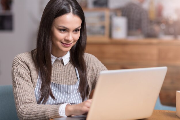 Buscando Algo Nuevo Encantadora Mujer Hermosa Sonriendo Y Sentado En La Mesa Mientras Usa La