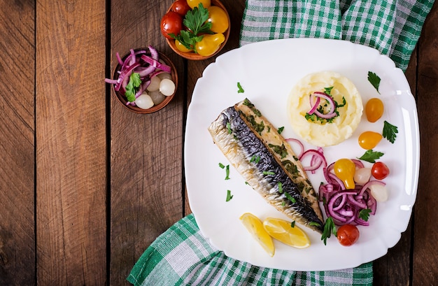 Caballa al horno con hierbas y adornada con puré de papas y verduras en