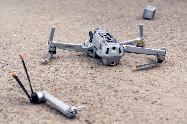 La caída del dron. un quadcopter volador roto yace sobre el asfalto, la hélice se ha volado y la cámara está dañada. | Foto Premium