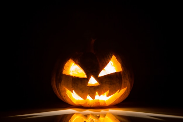 Calabaza de halloween con luz dentro y en un fondo negro | Foto Gratis