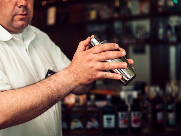 Camarero de sexo masculino que prepara la bebida en coctelera Foto gratis