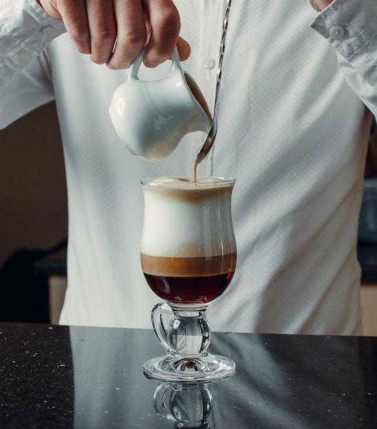 Camarero vertiendo caramelo en la bebida de café de tres