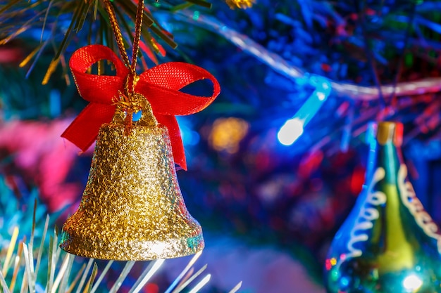 Campana De Navidad Dorada Con Cinta Roja Contra La Guirnalda De Colores