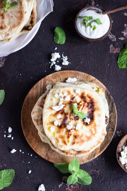 Cebolla, menta y queso pequeños panes planos servidos en un plato de madera. gozleme Foto Premium