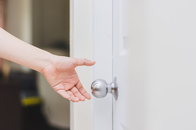Cerca de la mano de la mujer llegando a la perilla de la puerta, abriendo  la puerta | Foto Premium