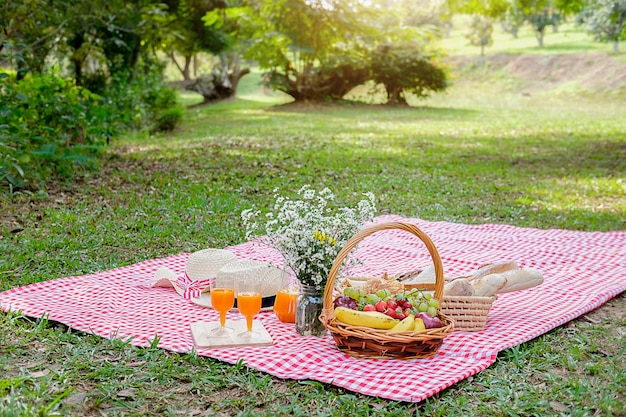 Cesta de mimbre de flores y picnic y jugo de naranja | Foto Premium