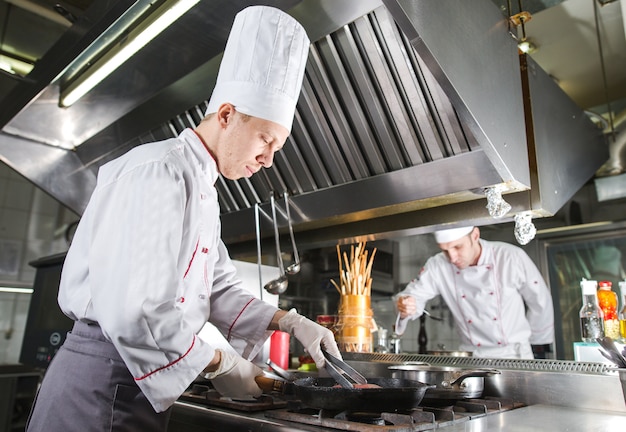 Chef En La Cocina Del Restaurante En La Estufa Con Pan Cocina Foto