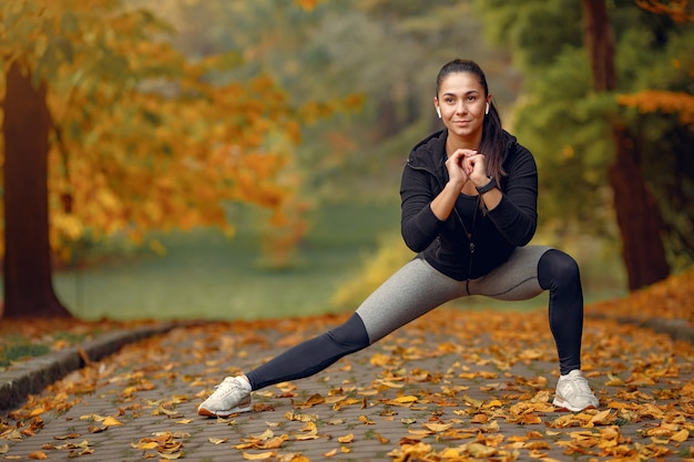 Chica deportiva en un top negro entrenamiento en un parque de otoño Foto gratis
