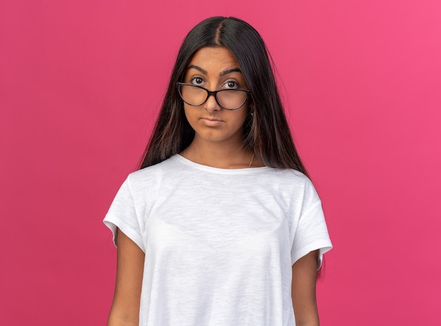 Chica joven en camiseta blanca con gafas mirando a la cámara con