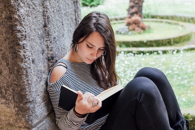 Chica leyendo un libro en la calle | Foto Gratis