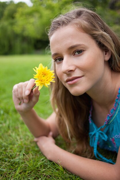 Chica Relajada Joven Tumbado En La Hierba En Un Parque Mientras Sostiene Una Flor Foto Premium