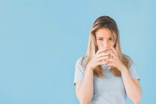 Chica rubia bebiendo vaso de agua Foto gratis