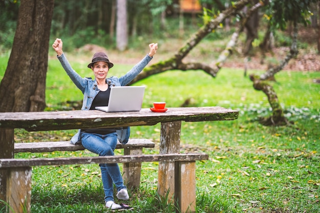 Chica trabajando y bebiendo café en la mesa en el bosque en ...