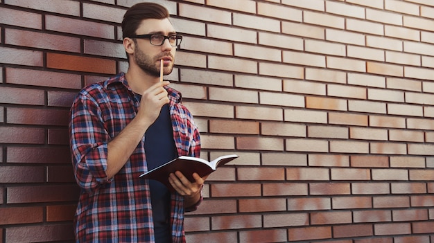 Chico Joven Inconformista Con Anteojos Leyendo Un Libro O Cuaderno