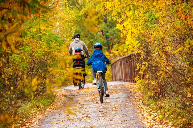 Ciclismo familiar en el parque de otoño dorado padre activo e hijos