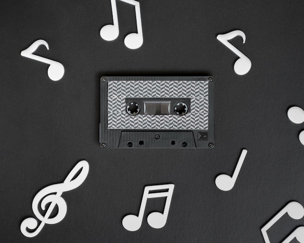 Cinta de cassette oscura con notas musicales blancas que la rodean Foto gratis