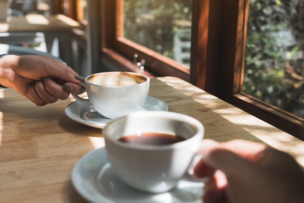 Closeup imagen de dos personas sosteniendo y tomando café en la mañana |  Foto Premium